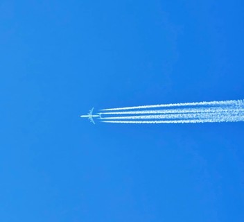 Aibus 380 widebody aircraft of Qatar Airlines with contrails in blue sky