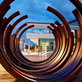 Modern sculpture of Bernar Venet with the inner city in the evening
