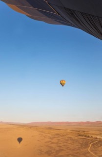 Hot-air balloon above a sandy plain at the edge of the Namib Desert
