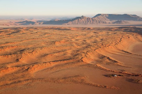 Farmhouse at the foot of a large grass-grown dune at the edge of the Namib Desert