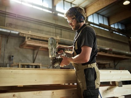 Carpenter nailing chipboard to a wooden beam