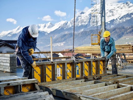 Construction workers lifting shuttering wall with crane
