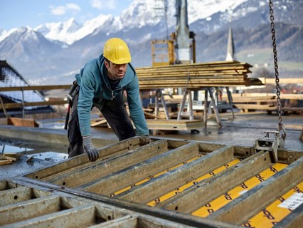 Construction worker lifting shuttering wall with crane