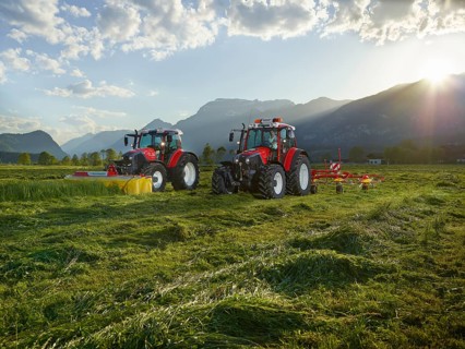 Two tractors mowing and tedding the cut hay