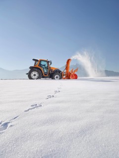 Tractor with a snow blower clearing snow