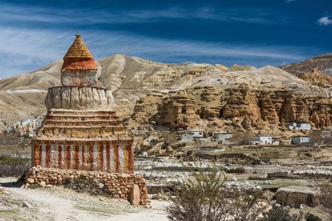 Colourfully painted Buddhist stupa in front of mountain landscape
