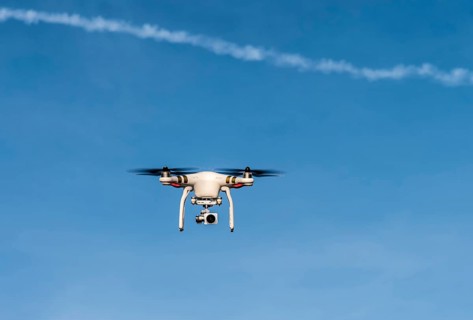 Quadcopter with camera flying in front of a blue sky