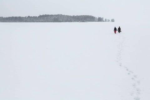 Two people walking over a frozen lake in the Arctic Circle