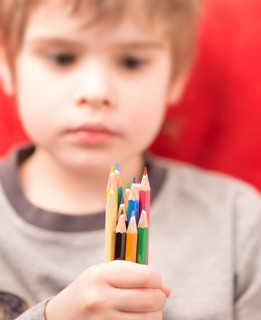 Serious looking girl holding coloured pencils in her hand