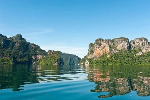 Forested karst limestone mountains reflected in the water