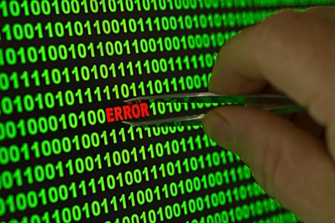 Hand reaching for the word 'Error' with tweezers in a binary code