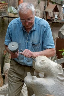 Sculptor working with hammer and chisel on hippopotamus figure