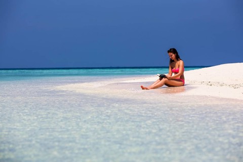 Woman with a book sitting on the beach
