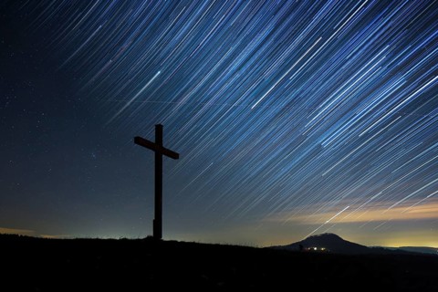 Summit cross on Bisberg Mountain with a starry sky