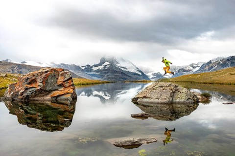 Hiker jumps on rocks in the lake