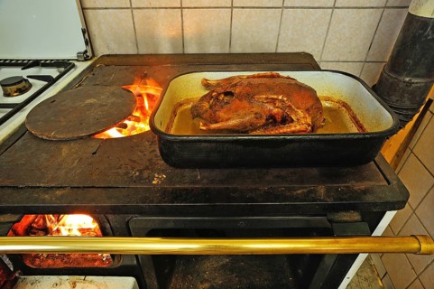 Ready roast duck in a roasting pan on an old coal-fired stove with open fire plate