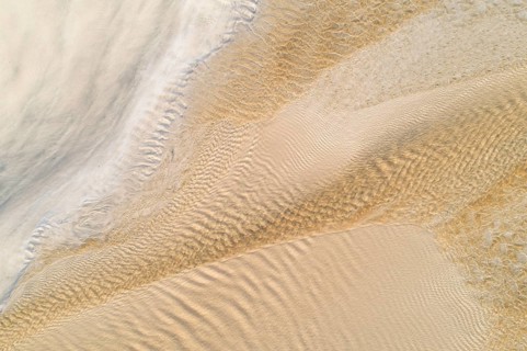 Water flows over a sandy beach at low tide