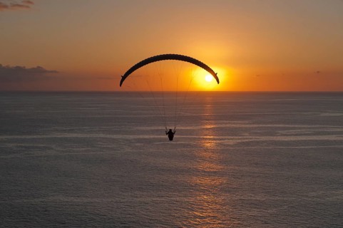 Paraglider over the Atlantic Ocean with sunset