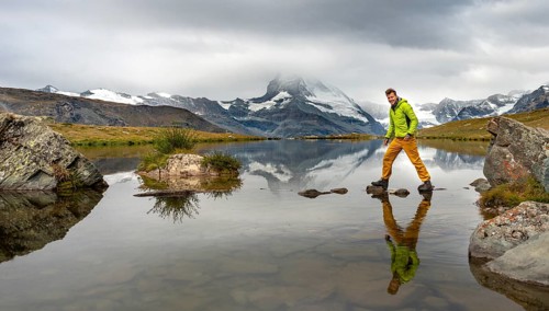 Hiker walks over stones in the water