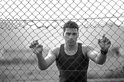 Young man holding onto a fence