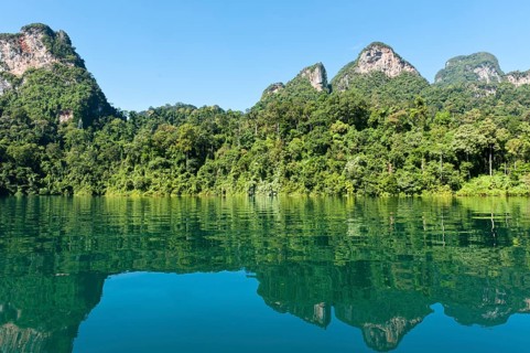 Forested karst limestone mountains with jungle vegetation reflected in the water