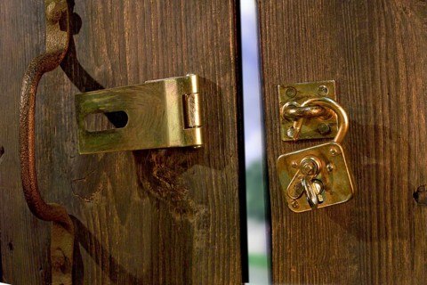 Old wooden door with metal fittings and an open padlock