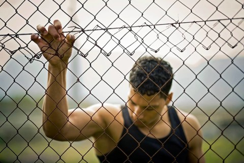 Young man holding onto a fence