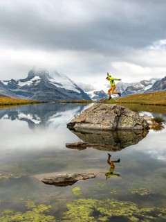 Hiker jumps on rocks in the lake