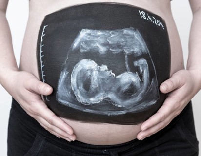 Pregnant woman with a body paint of an ultrasound image on her belly