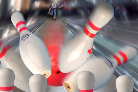 Bowling pins being hit by a red bowling ball