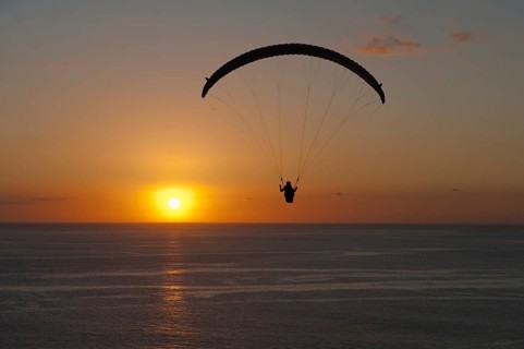Paraglider over the Atlantic Ocean with sunset