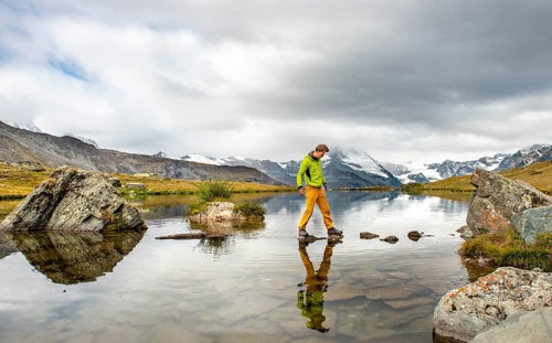 Hiker walks over stones in the water
