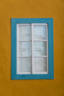 Turquoise coloured window with a yellow facade