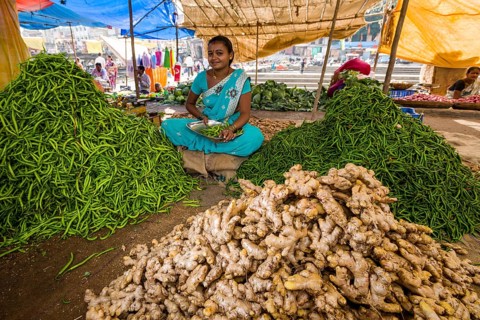 A woman is selling ginger and chilis at the weekly vegetable market