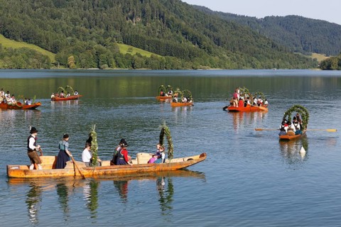 Locals wearing traditional costumes in decorated wooden Platte boats