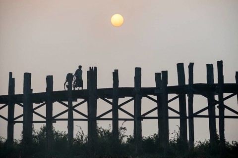 Man with a bicycle on a teak bridge