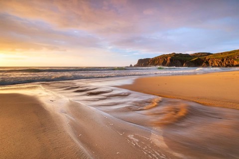 A brook flows over the sandy beach into the sea