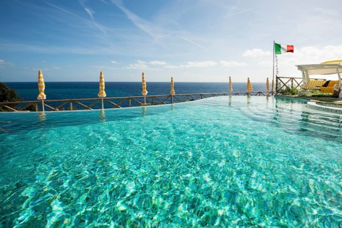 Swimming pool and the Mediterranean with the flag of Italy