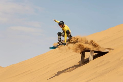 Sand boarding in the dunes of the Namib Desert