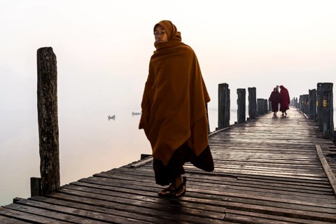 Monks walking on a teak bridge