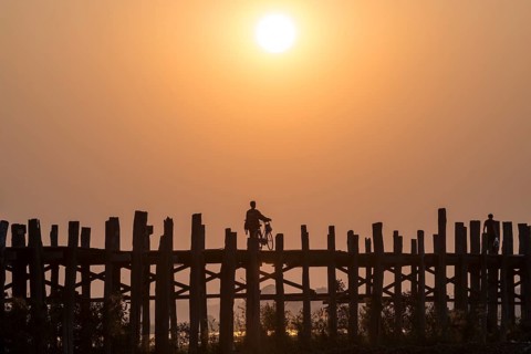 Man riding a bike on a teak bridge