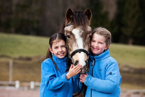 Two girls standing beside a pony