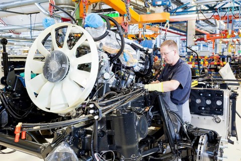 Employee installing the engine and transmission in a chassis at MAN Truck and Bus AG