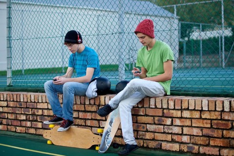 Two teenage boys sitting on a brick wall
