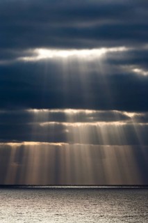 Sun rays shine through dark storm clouds