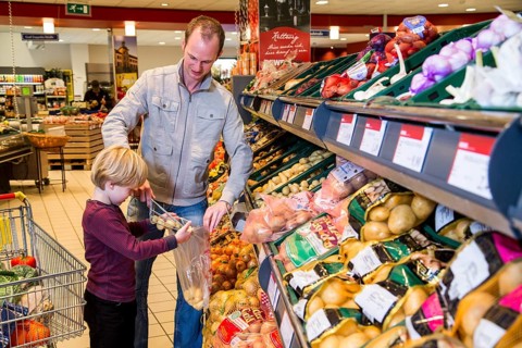 Family shopping with a shopping trolley in the fruit and vegetables department of a supermarket