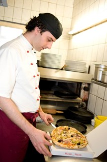Pizza baker putting a pizza in a pizza box