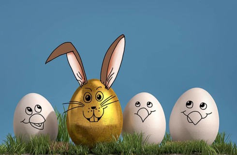 Three white eggs with painted chicken faces chicks and one golden egg with a painted rabbit face