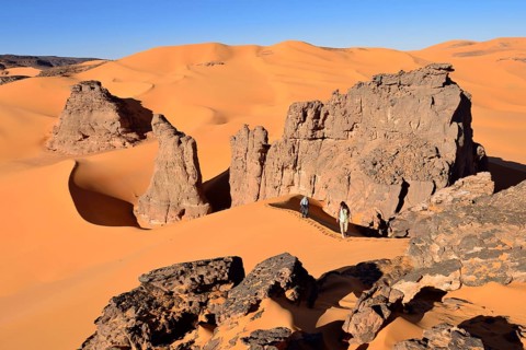 People hiking in the sand dunes and rocks of Moul Naga
