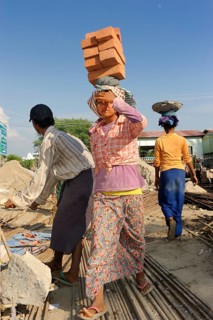 Female construction workers carry bricks on their heads